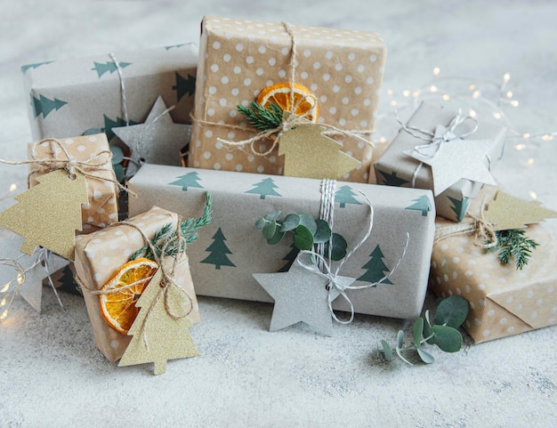Coffrets cadeaux faits maison décoratifs de Noël enveloppés dans du papier kraft brun sur fond de béton gris