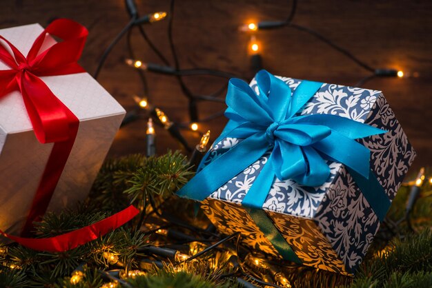 Coffrets cadeaux de noël avec des arcs rouges et bleus et des lumières sur une surface en bois