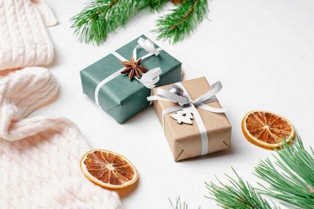 Coffrets cadeaux de noël décorés avec des oranges sèches et des branches de pin sur blanc