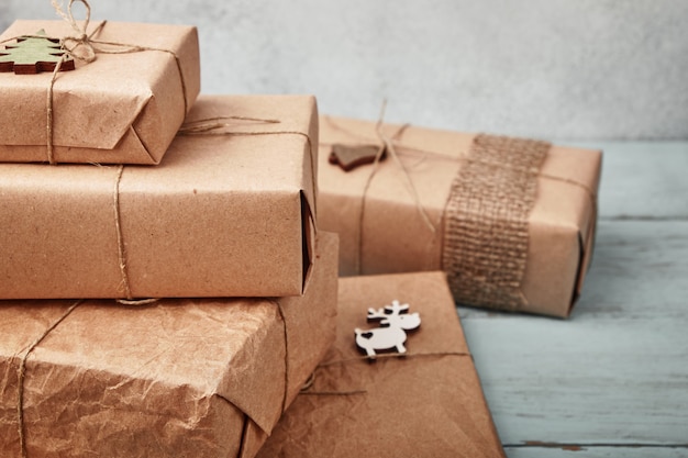 Coffrets cadeaux de Noël emballés dans du papier kraft sur une table en bois bleue.