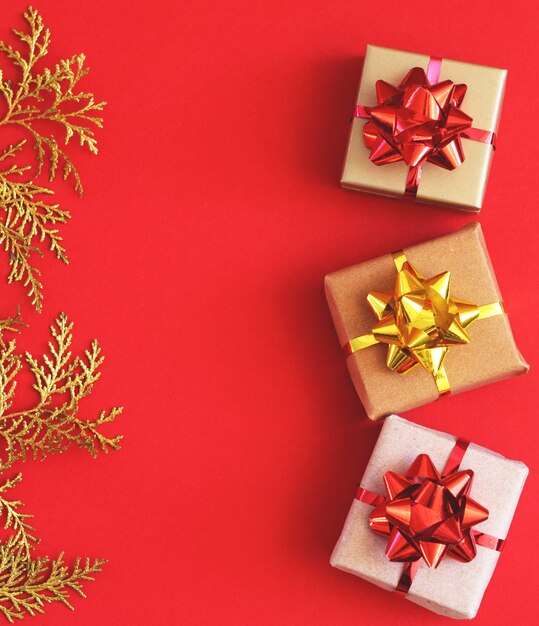 Coffrets cadeaux de Noël faits à la main en papier kraft. Boîtes et brins dorés sur fond rouge. Copier spase