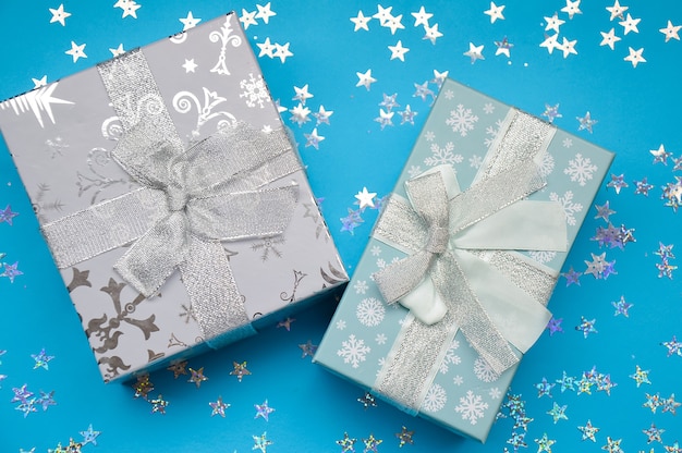 Coffrets cadeaux de Noël sur fond bleu avec carte de nouvel an paillettes et flocons de neige