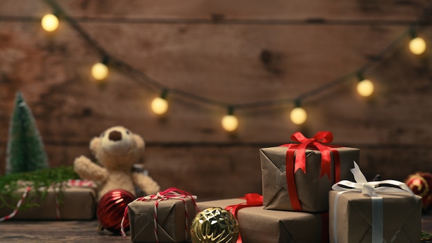 Coffrets cadeaux de Noël, ours en peluche et décorations d'ornements de Noël sur table en bois.