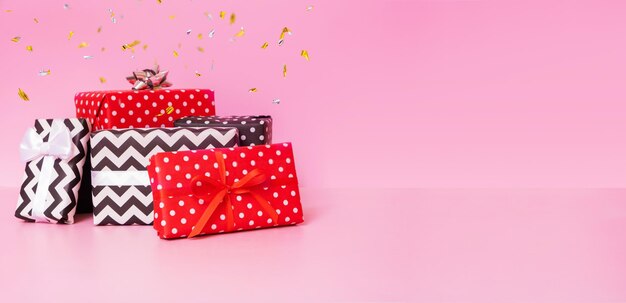 Coffrets cadeaux avec noeud de ruban et konfetti sur fond rose Joyeux Noël Nouvel an et concept d'événement de vente