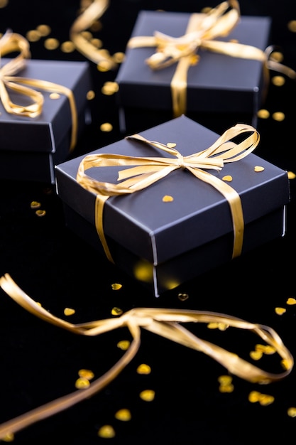 Coffrets cadeaux noirs avec ruban d'or sur fond brillant