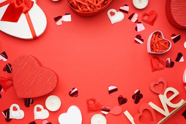 Coffrets cadeaux pour la Saint-Valentin et confettis sur fond rouge, espace pour le texte, vue de dessus.