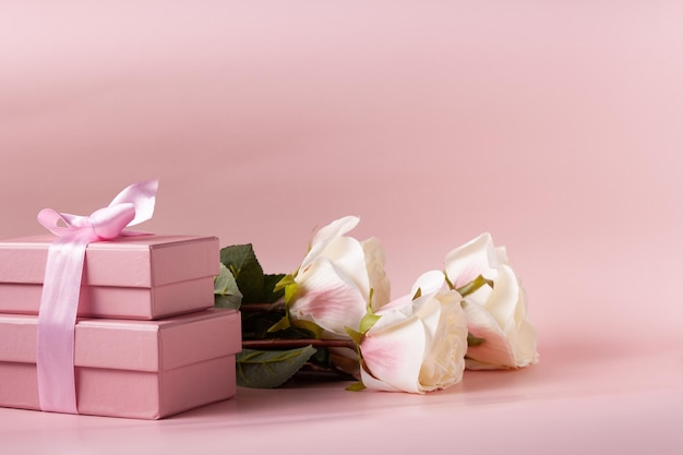 Coffrets cadeaux roses et un bouquet de roses blanches sur un espace de copie de fond rose