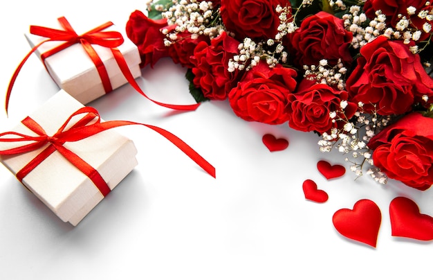 Coffrets cadeaux de la Saint-Valentin et bouquet de roses rouges sur une surface blanche