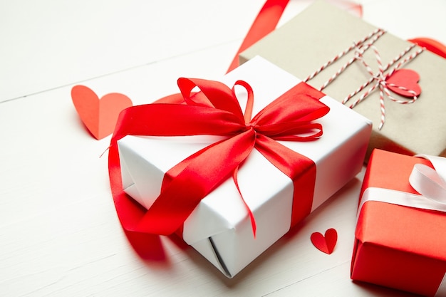 Coffrets cadeaux Saint Valentin et coeurs en papier rouge sur table en bois blanc