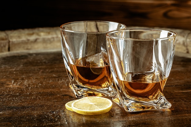 Photo cognac dans des verres avec des morceaux de citron sur une table en bois