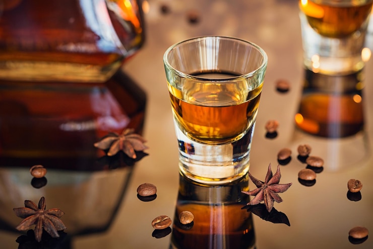 Photo cognac ou liqueur grains de café et épices sur une table de verre concept de vacances de saison