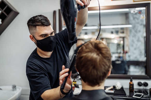 Coiffer les cheveux des hommes. Barber fait une coiffure élégante. Style de vie dans un salon de coiffure.