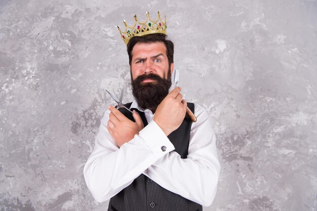 Photo coiffer les cheveux de manière appropriée coiffeur professionnel dans un salon de coiffure grand patron avec moustache et barbe tenant des outils de rasage homme barbu coupé les cheveux avec des ciseaux et un rasoir salon de coiffure de luxe