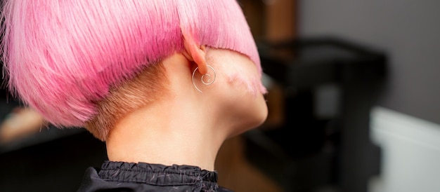 Coiffer et couper les cheveux roses teints du jeune mannequin vue arrière dans un salon de coiffure. Coiffure courte rose.