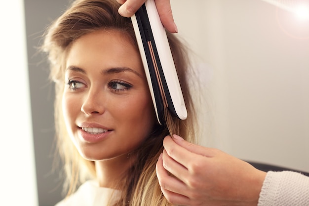 Coiffeur à l'aide d'un fer à lisser en studio