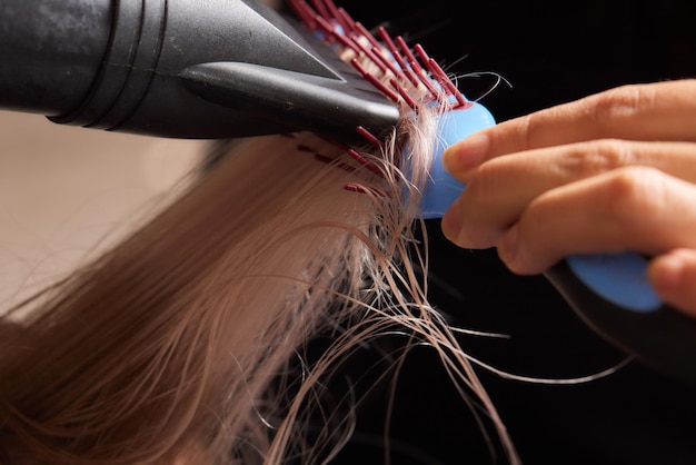 Le coiffeur Airtouch fait bouffant à l'aide d'un peigne sur des mèches fines Technique Shatush pour éclaircir les cheveux