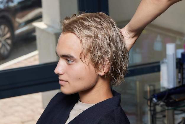 Le coiffeur Airtouch fait bouffant à l'aide d'un peigne sur des mèches fines Technique Shatush pour éclaircir les cheveux