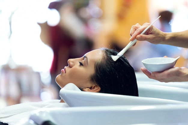 Photo le coiffeur appliquant le traitement des cheveux pour le client dans un salon de beauté.