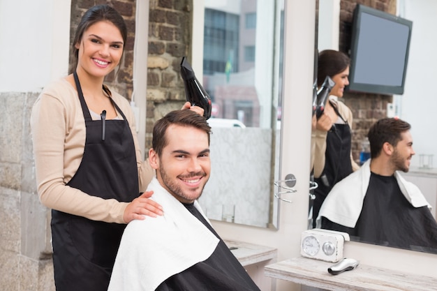 Coiffeur et client souriant à la caméra