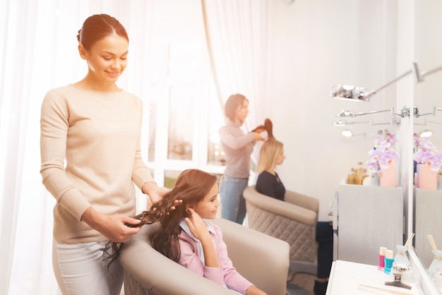 Coiffeur coiffant une petite fille aux cheveux noirs.