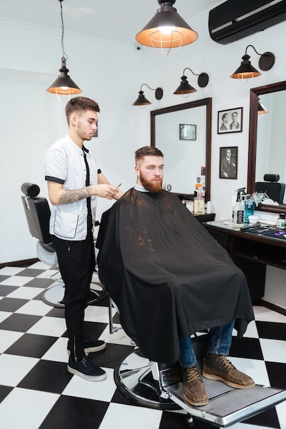 Coiffeur coupant les cheveux d'un client masculin dans un salon de coiffure