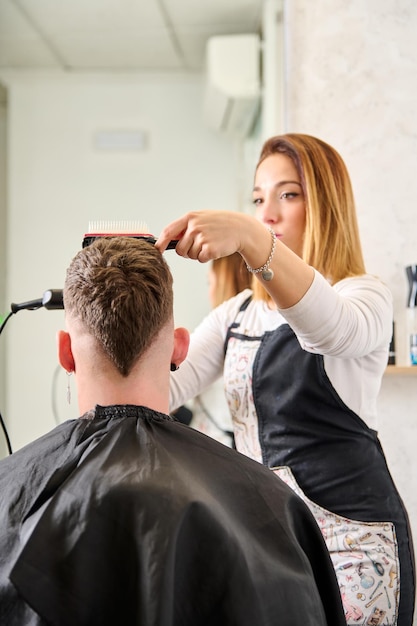 Coiffeur coupant les cheveux et coiffant un client dans le salon de coiffure