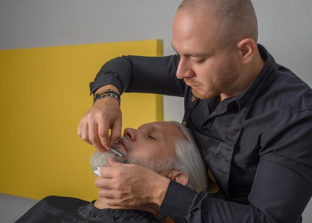 Coiffeur coupant et coiffant la barbe d'un homme aux cheveux gris B Salon de coiffure pour hommes