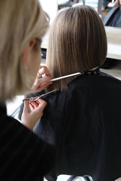 Coiffeur coupe les cheveux bruns avec des ciseaux