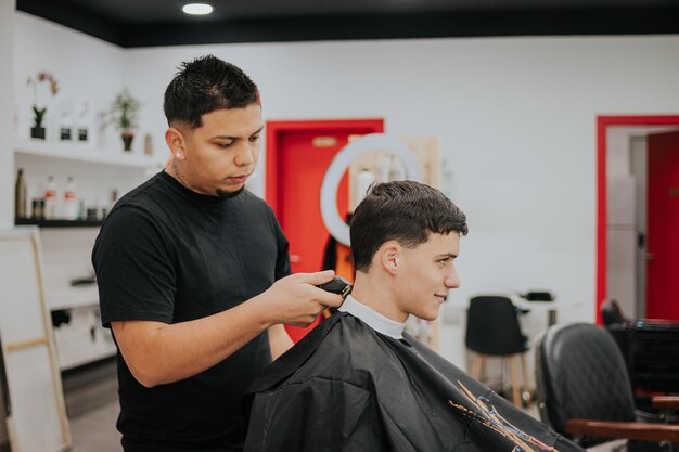 Photo un coiffeur coupe les cheveux d39un garçon avec une machine