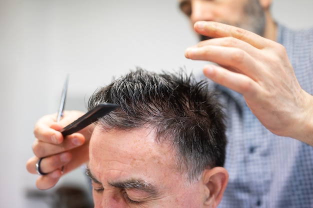 Coiffeur coupe les cheveux du vieil homme au salon de coiffure.