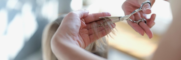 Le coiffeur coupe les cheveux de femme avec le plan rapproché de main de ciseaux