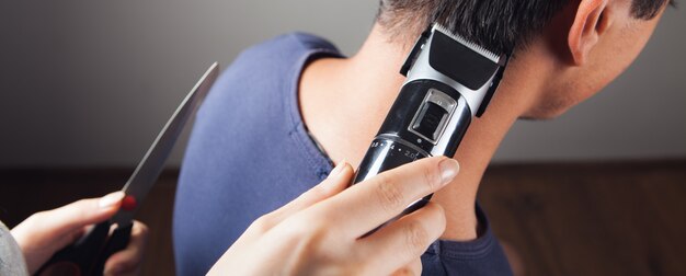 Le coiffeur coupe les cheveux d'un homme avec une tondeuse