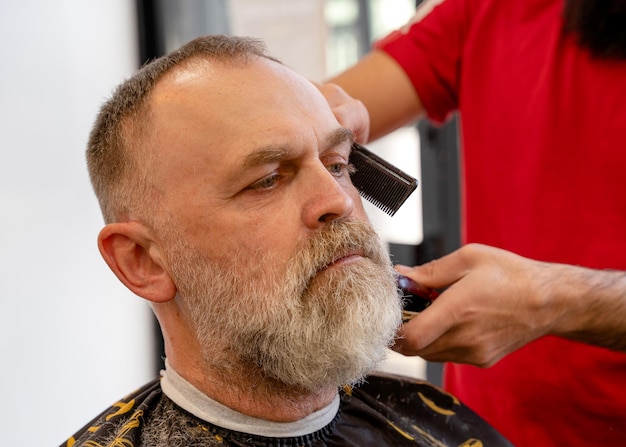 Coiffeur coupe et coupe homme barbu avec machine à raser dans un salon de coiffure