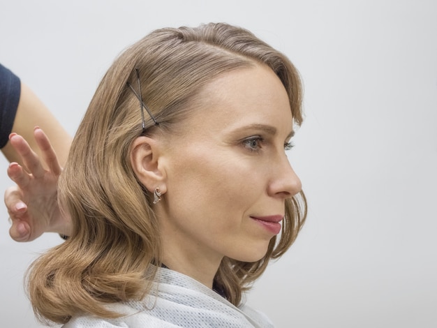 Photo le coiffeur crée l'image de la blonde mariée. fermer.