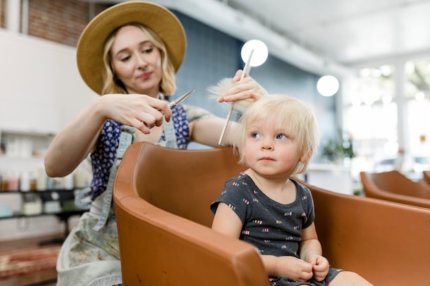 Coiffeur donnant une coupe de cheveux à un adorable gosse blond