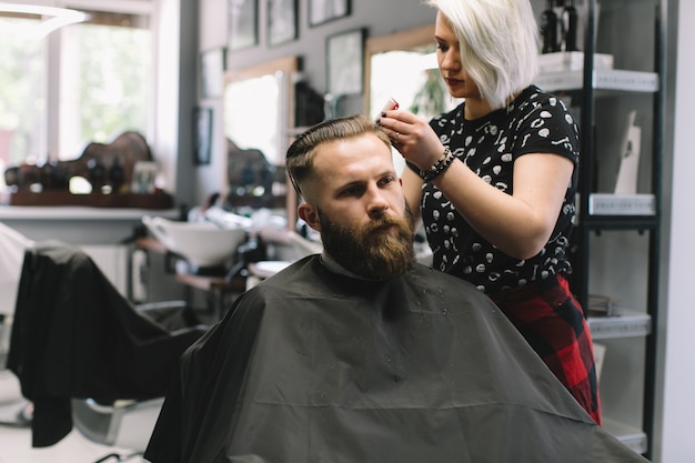 Coiffeur élégant couper les cheveux du client au salon de coiffure.