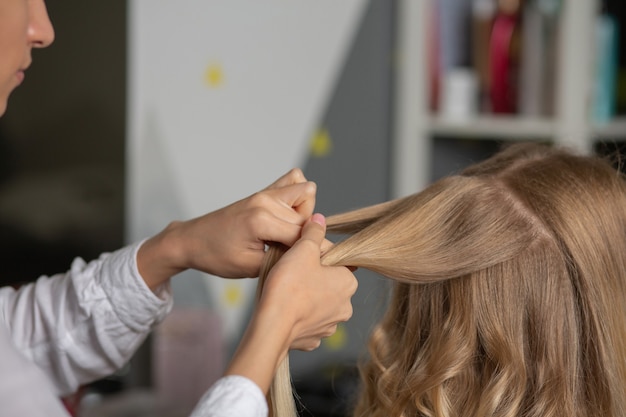 Le coiffeur fait la coiffure à une cliente blonde au salon de coiffure