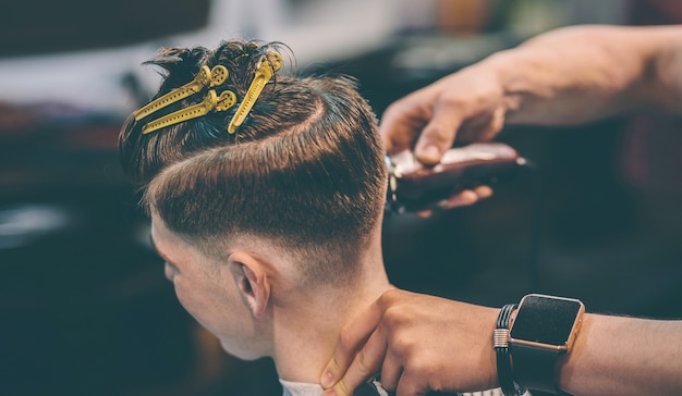 Coiffeur fait coiffure un homme avec un clip sur la tête dans un salon de coiffure