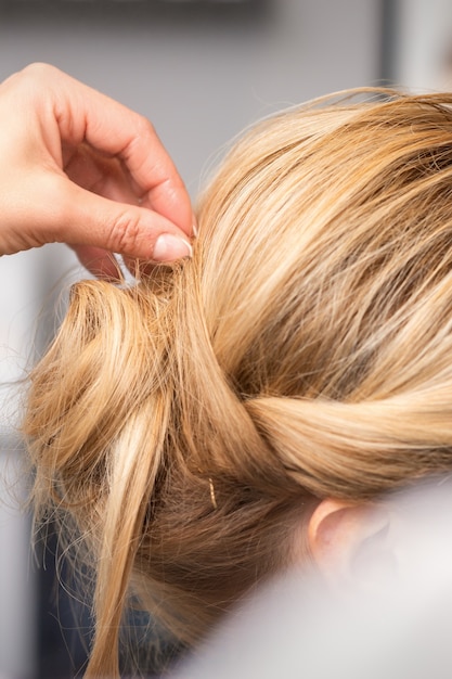 Le coiffeur fait la coiffure de la jeune femme