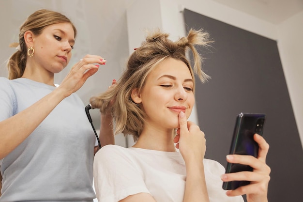 Le coiffeur fait la coiffure jolie jolie jeune femme dans le salon de beauté