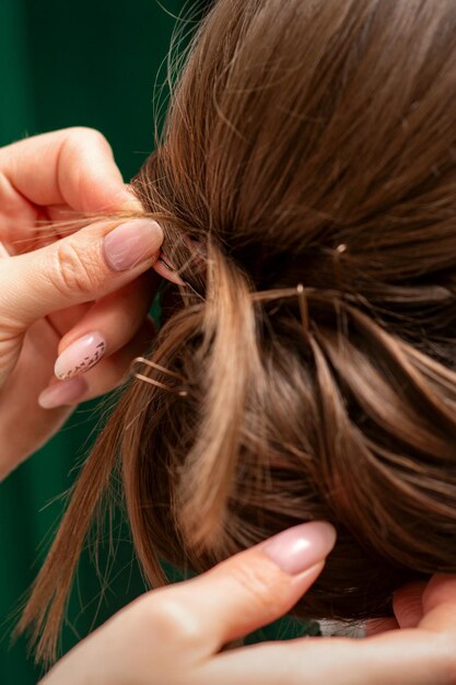 Le coiffeur fait des coiffures pour une jeune femme dans un salon de beauté en gros plan.