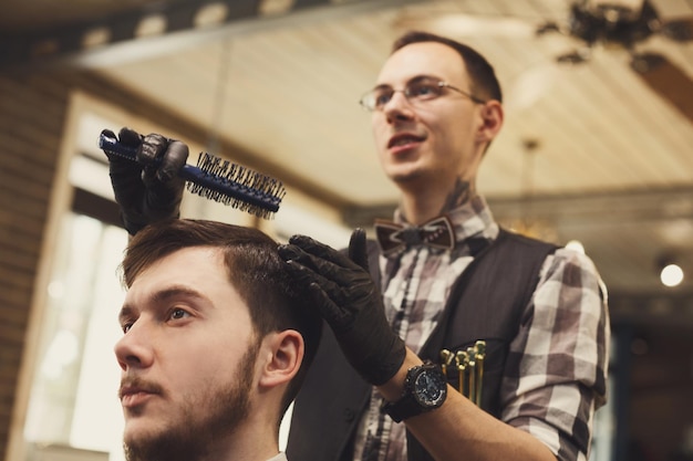 Photo le coiffeur fait la coupe de cheveux dans le salon de coiffure. coiffure dans un salon de coiffure pour hommes