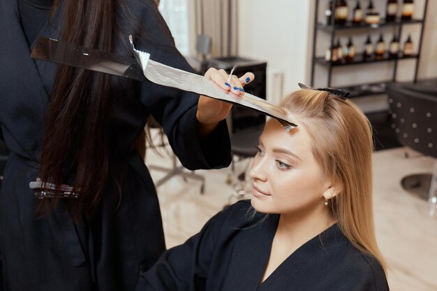 Le coiffeur fait du bouffant à l'aide d'un peigne sur des mèches fines. Technique Shatush pour éclaircir les cheveux.