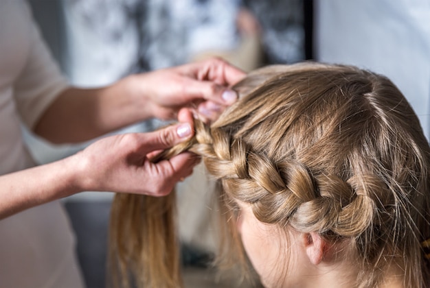 Coiffeur fait des tresses dans un salon de beauté