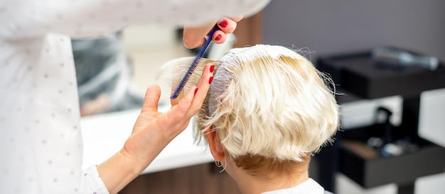 Coiffeur féminin coiffant les cheveux blancs courts de la jeune femme blonde