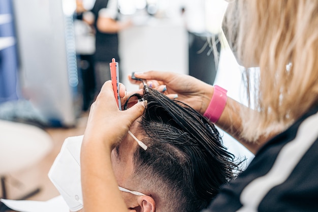 Coiffeur Féminin Peignant Les Cheveux D'un Homme Se Faisant Couper Les Cheveux Dans Un Salon De Coiffure