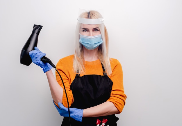 Coiffeur femme blonde portant un masque et des gants de médecine