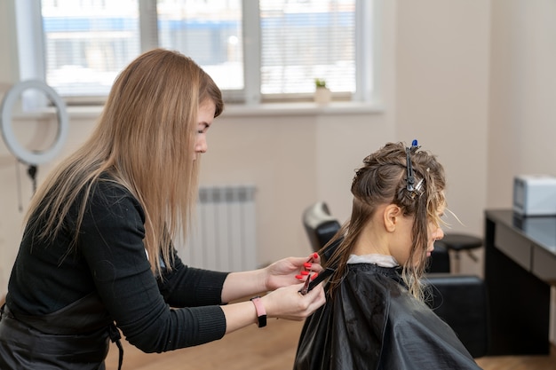 Photo coiffeur femme coupe les cheveux de la jeune femme