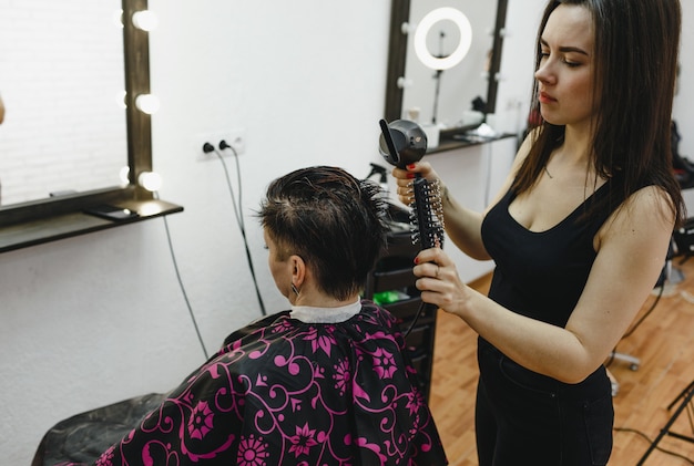 Un coiffeur fille fait une coiffure pour une cliente dans un salon de beauté moderne. L'art de la coiffure.