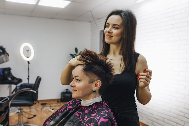 Un coiffeur fille fait une coiffure pour une cliente dans un salon de beauté moderne. L'art de la coiffure.